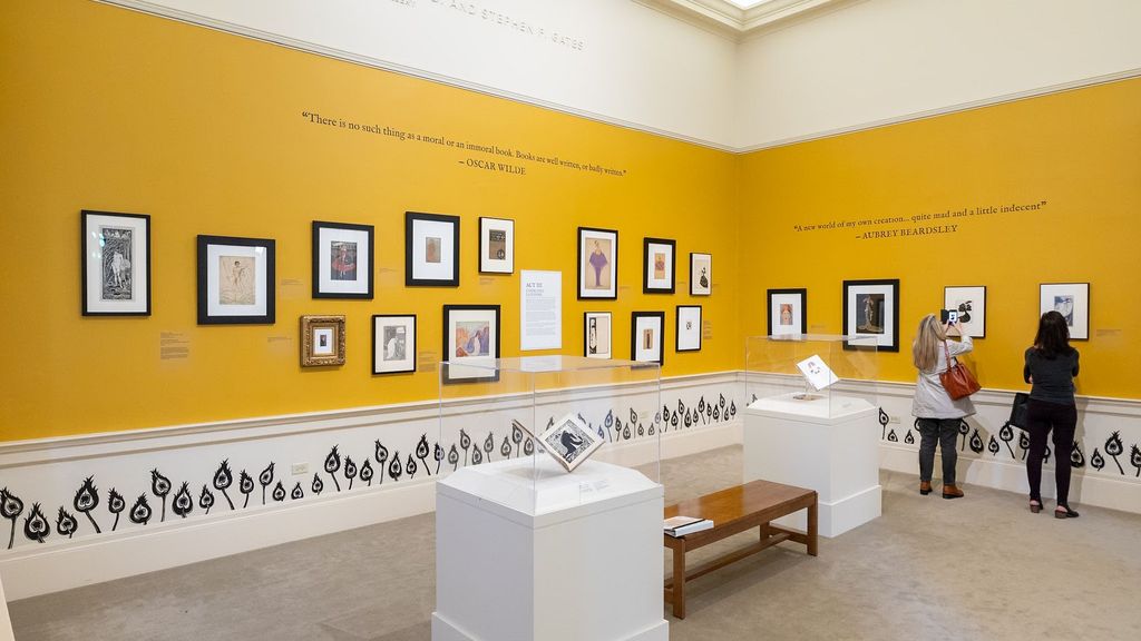 Photo: Interior of an art gallery with small pictures hung in black frames on a yellow wall