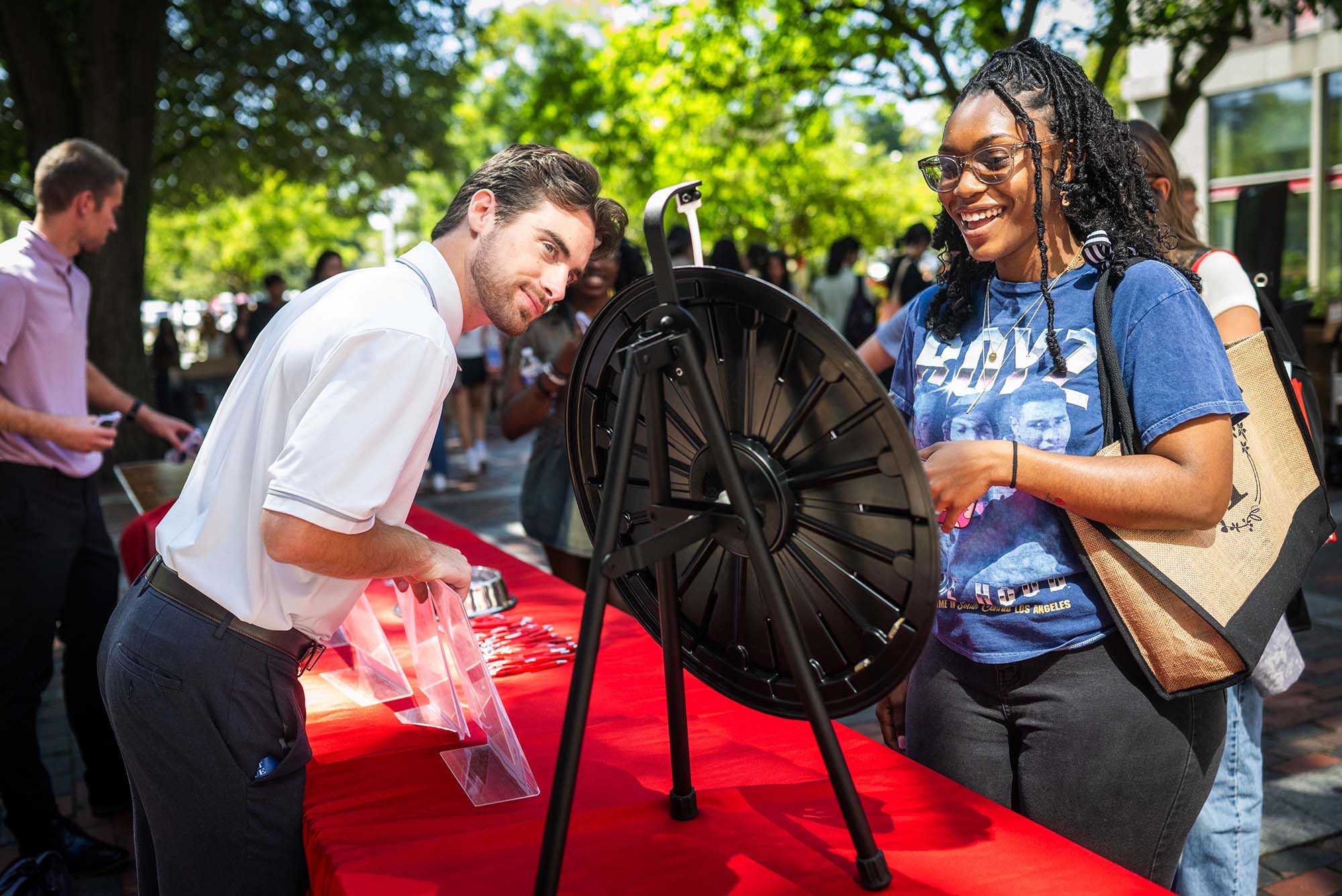 Photo: A woman visiting a table during a festival that has a wheel of prizes