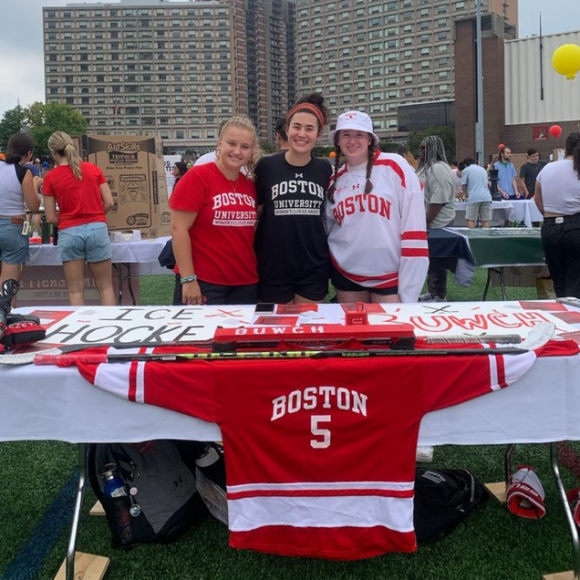 Photo: A group of college students wearing Boston University shirts stand behind a table promoting BU Women's ice hockey