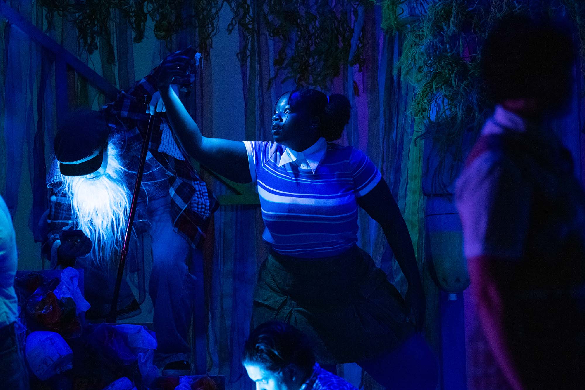 Photo: An actress onstage in the ensemble of "Spongebob the Musical." The lighting and set are blue to simulate being underwater and the actress has a wide-eyed expression and her arm extended