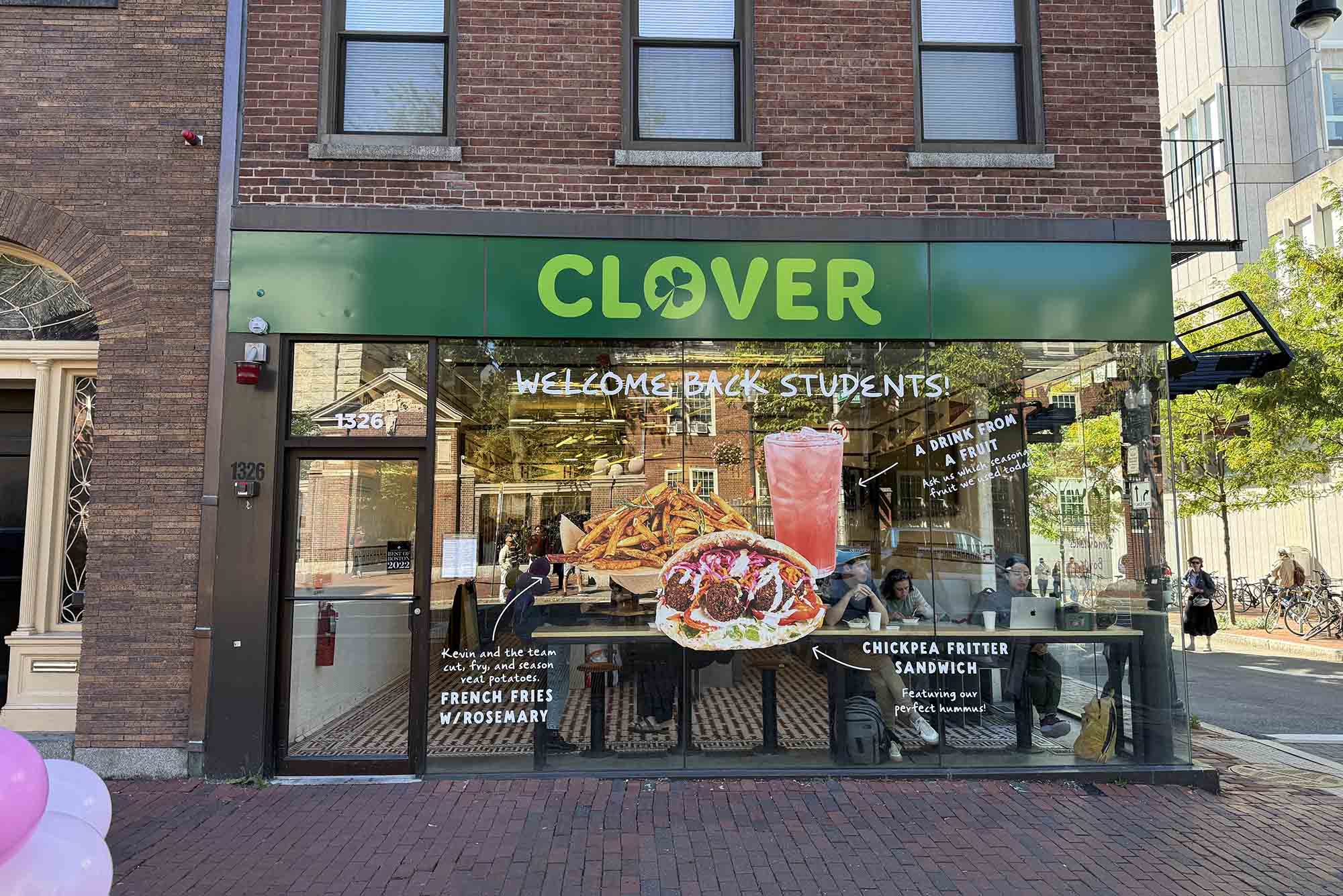 Photo: The storefront for Clover. A green banner with CLOVER sits on top of tall windows on a corner street store.