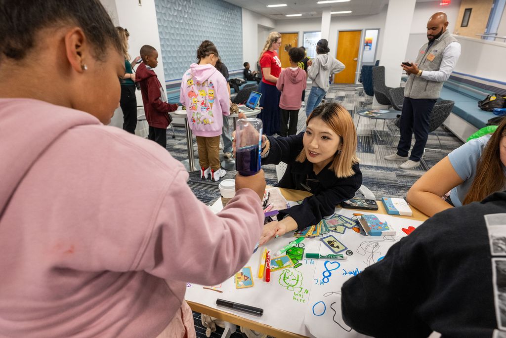 Photo: A grade school student doing a project with help from a young woman