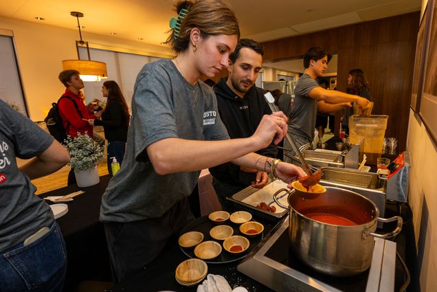 Photo: A picture of a female student pouring marinara on arancini while a man watches her