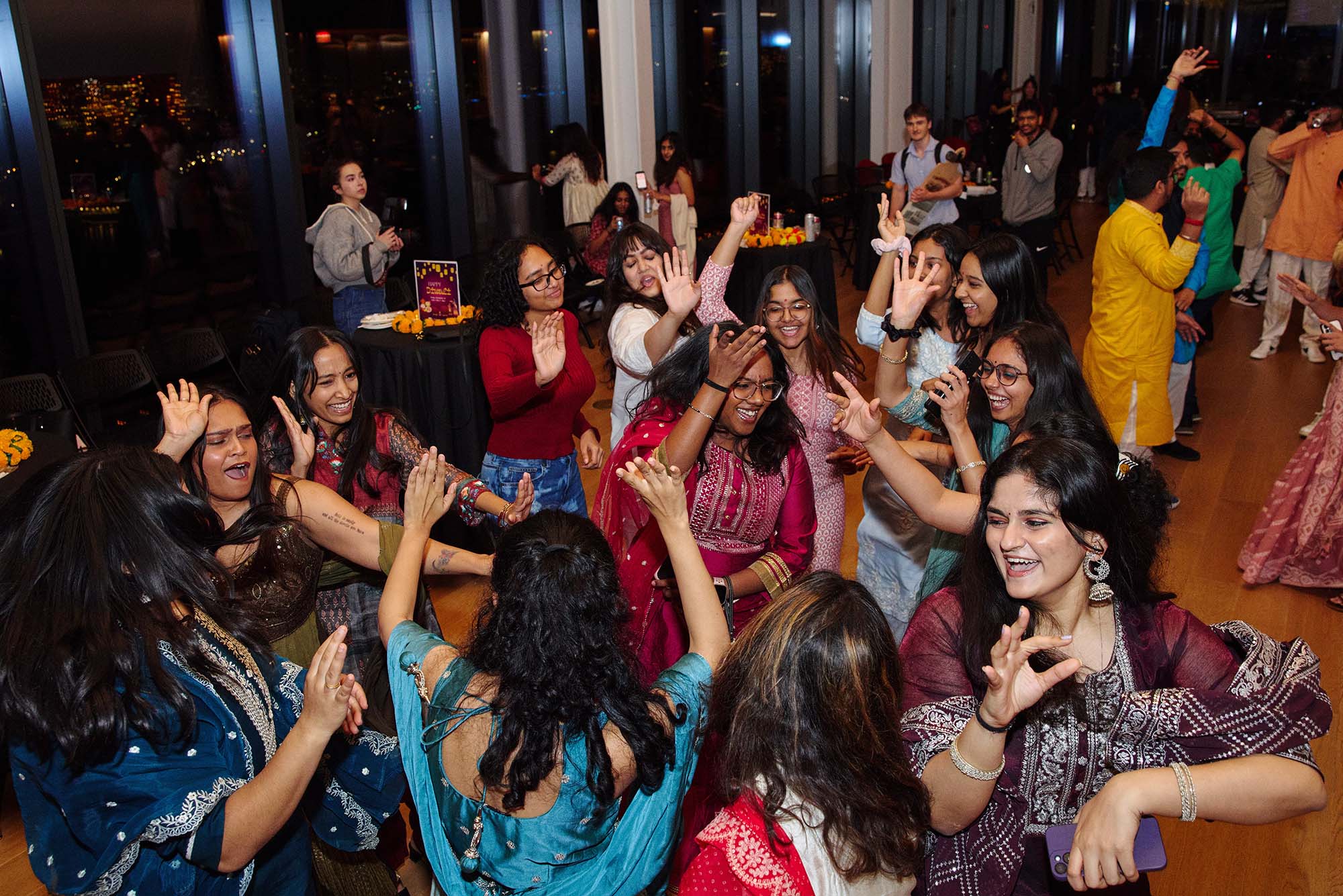 Photo: People dancing during a Diwali celebration, many wearing traditional saris.
