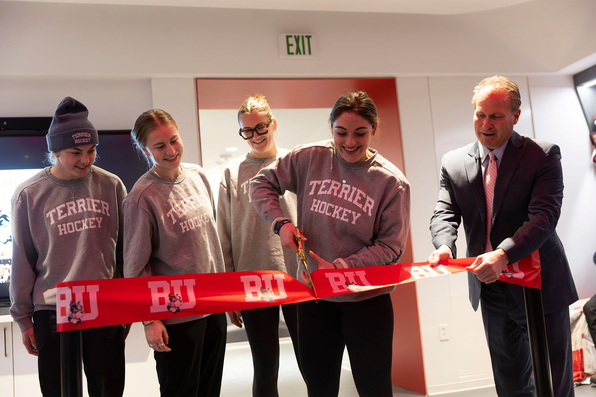 Photo: Women’s ice hockey assistant captain Callie Shanahan (COM’25, left), assistant captain Maggie Hanzel (Questrom’25), assistant captain Julia Shaunessy (CAS’24, SPH’25) captain Tamara Giaquinto (Questrom’24, SHA’25) and director of athletics Drew Marrochello at a ribbon cutting inside the new women’s ice hockey locker room at Walter Brown Arena, January 24. The new locker room was part of a complete renovation of the team’s spaces, including a new lounge, coaches’ offices, equipment room and athletic training room. This completed a $13 million project within the Case Center that include the Ike Brown (Questrom’76) Basketball Locker Room, which was unveiled to the men’s basketball team earlier this month along with the Todd & Anne Klipp Video Room, which will be used by both basketball programs. It was the most significant renovation project within an existing Athletics facility in department history. Photo by Matt Woolverton.