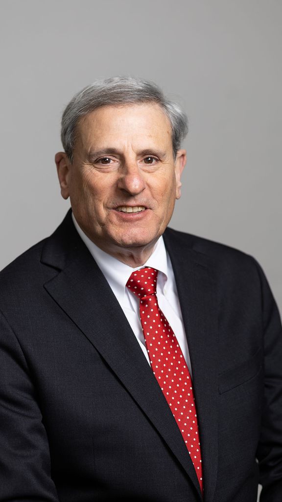 Photo: A man smiling for a portrait while wearing a dark suit and vibrant red tie