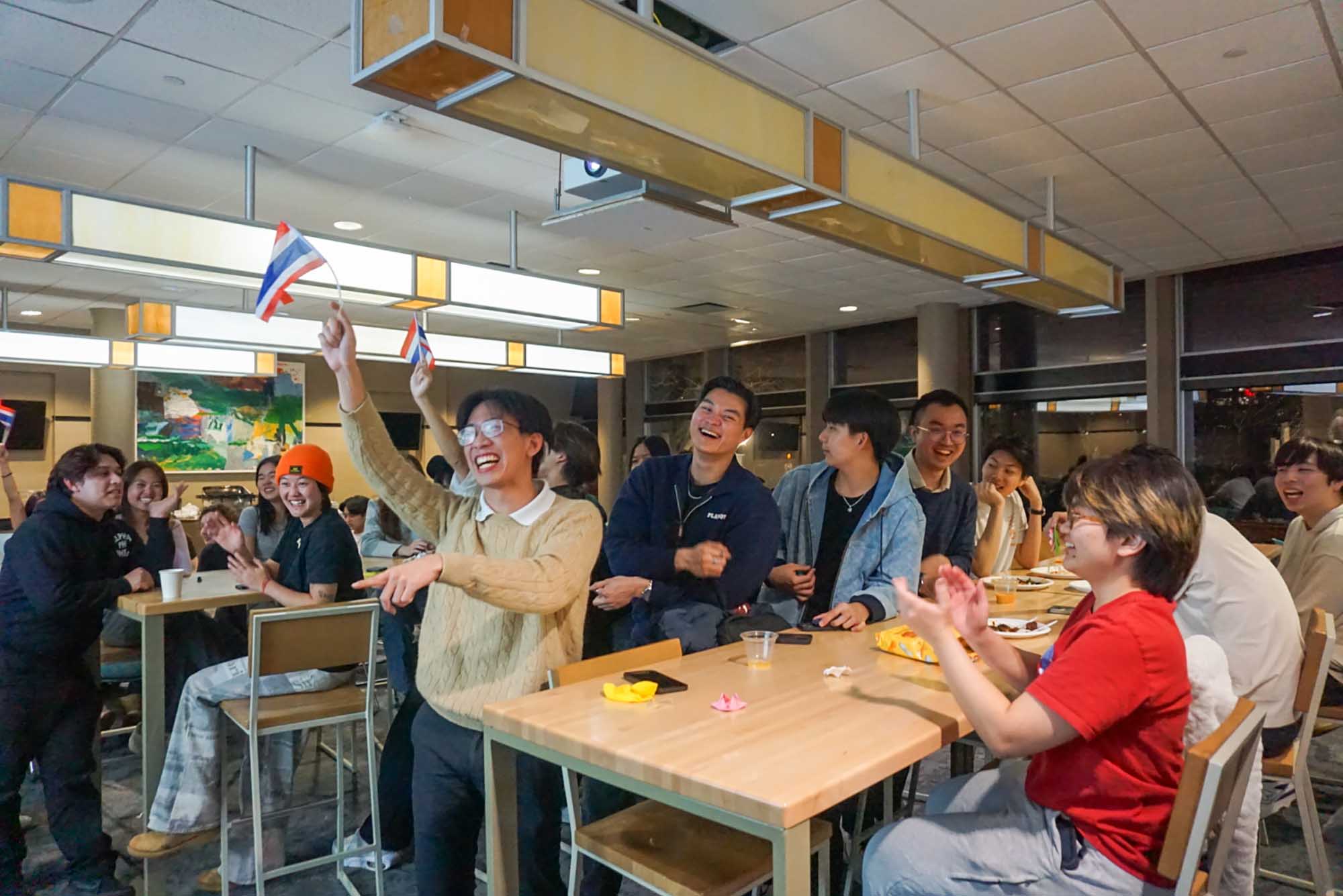Photo: A crowd of people smiling and celebrating Thai culture in a karaoke trivia game.