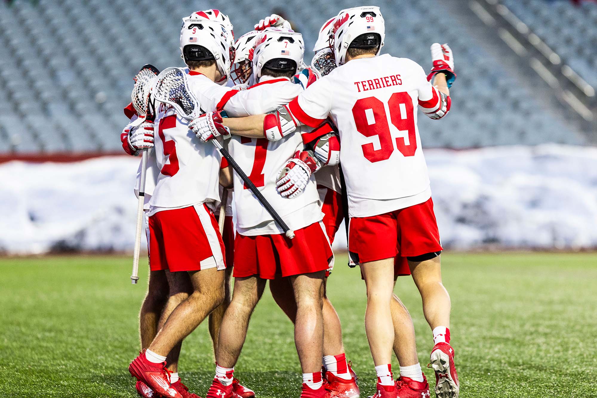 Photo: BU Lacrosse players with their arms around each other on a field