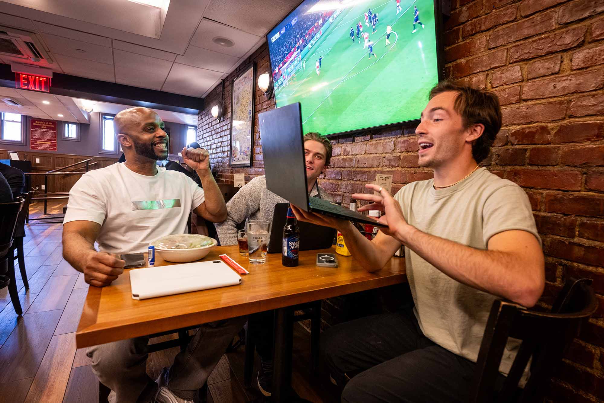Photo: A group of people at a table, one looking at a laptop.
