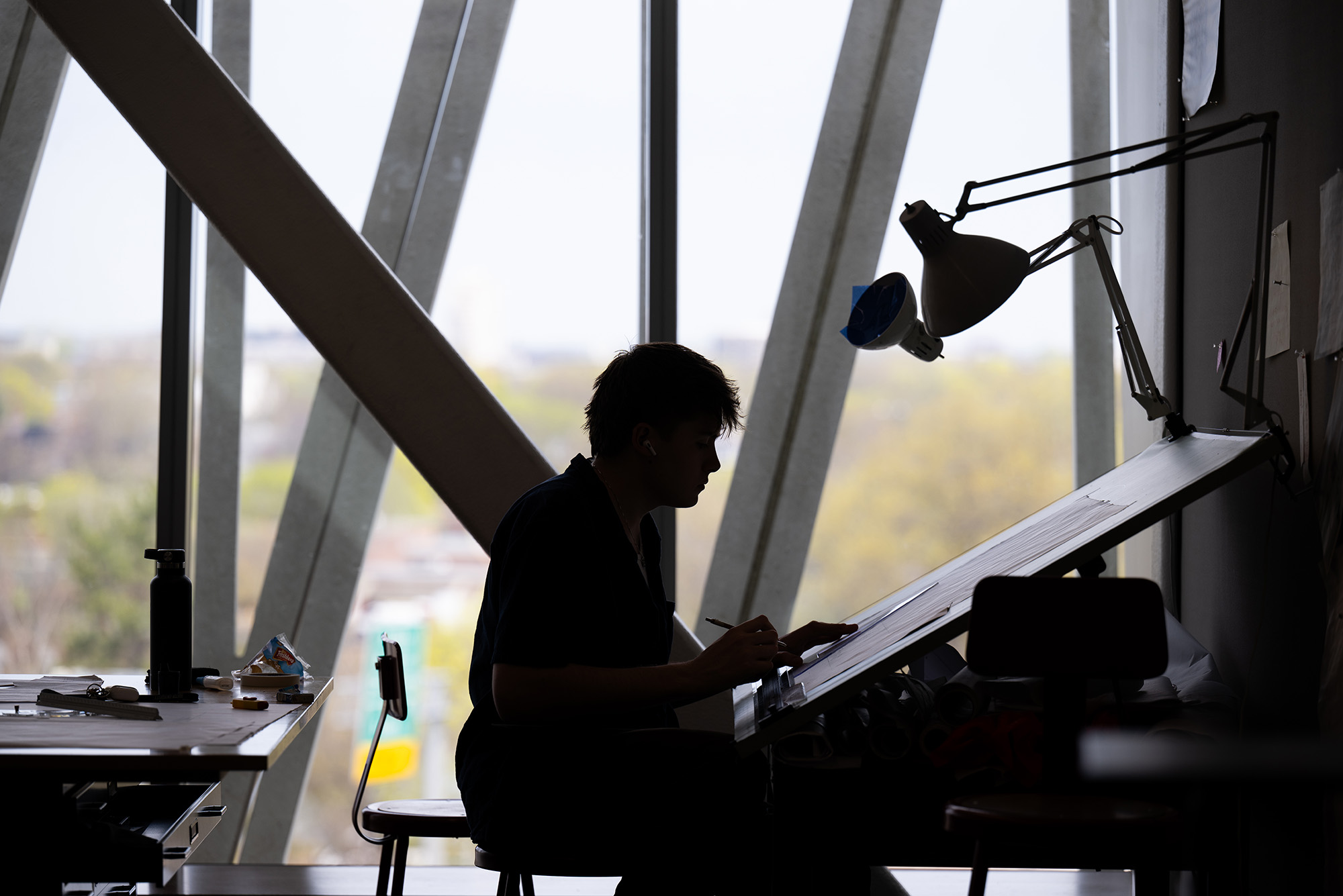 Photo: A shadow of a BU student drawing for a rendering class