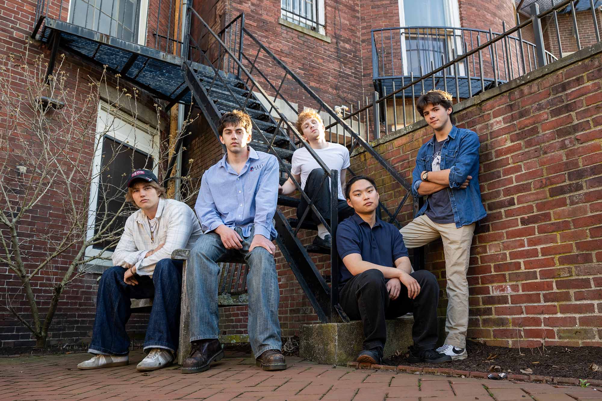 Photo: A band of 5 male members lined up and posing on a stairway in front of buildings