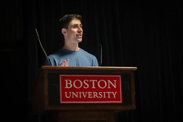 Photo: A white man with short brown hair and a dusty blue shirt on a podium.