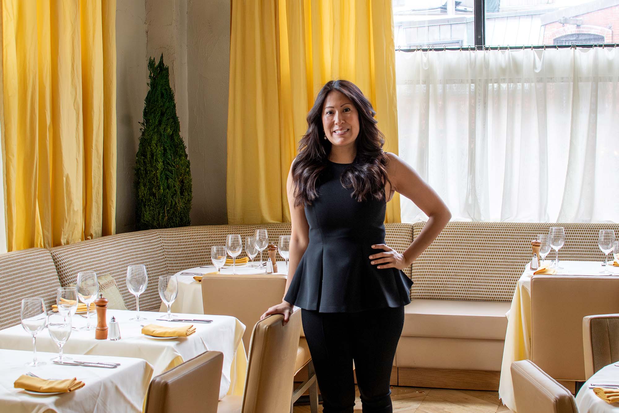 Photo: A woman posing with a hand on her hip in the middle of a fine dining room area