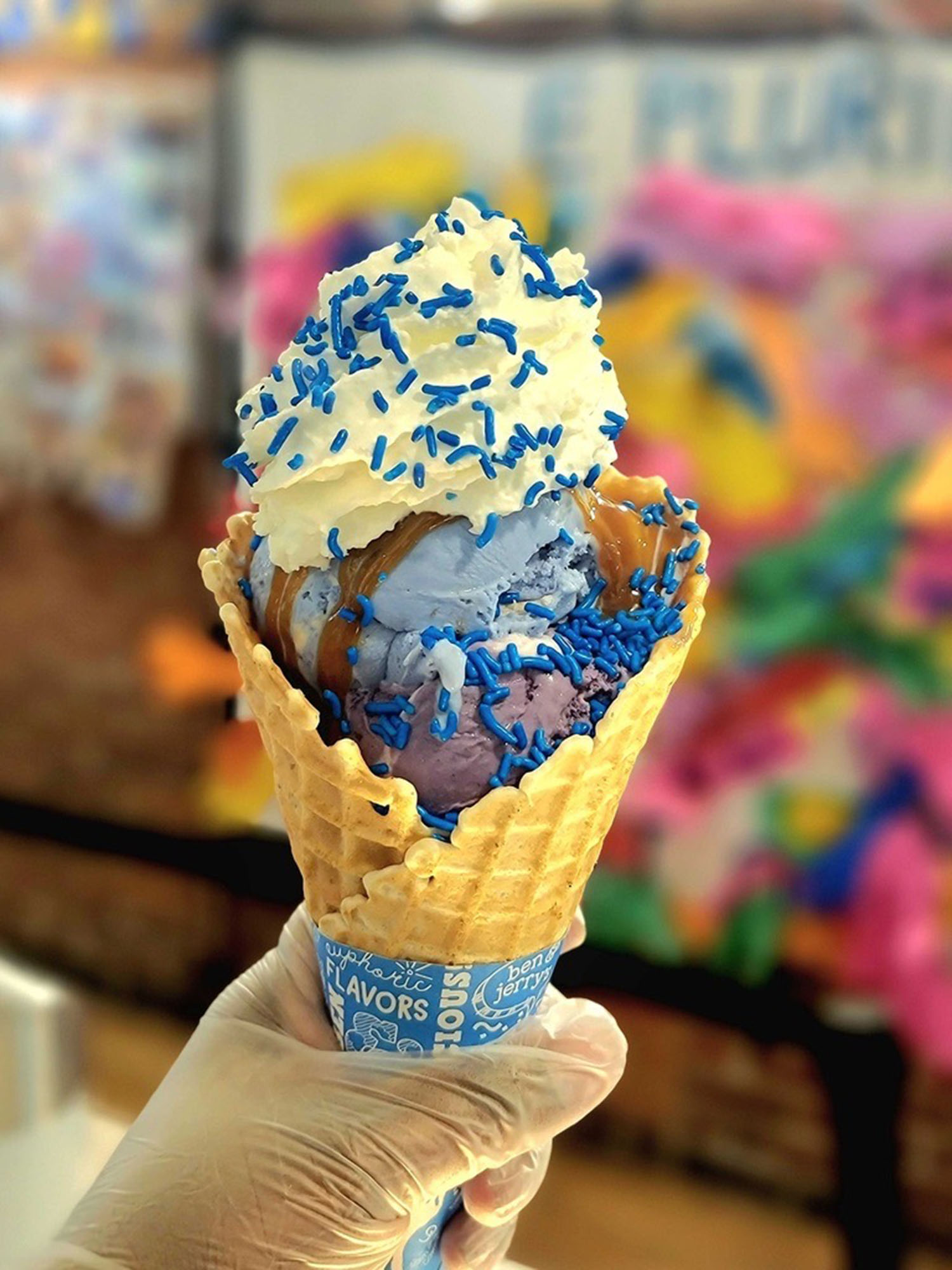 Photo: An ice cream cone with purple and blue scoops, whipped cream, and blue sprinkles on top