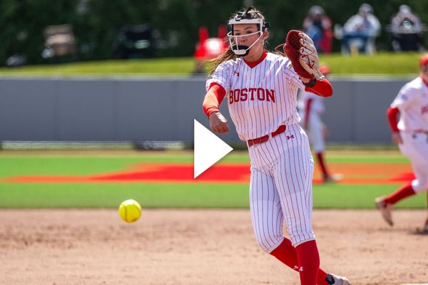 Photo: A female BU softball player pitching a ball during a game. There is a video play button over the image