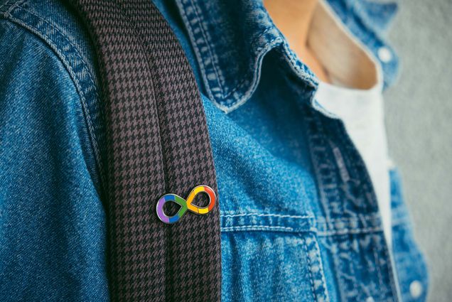 Photo: A boy wearing a jean jacket and an autism infinity rainbow symbol pin on his backpack strap