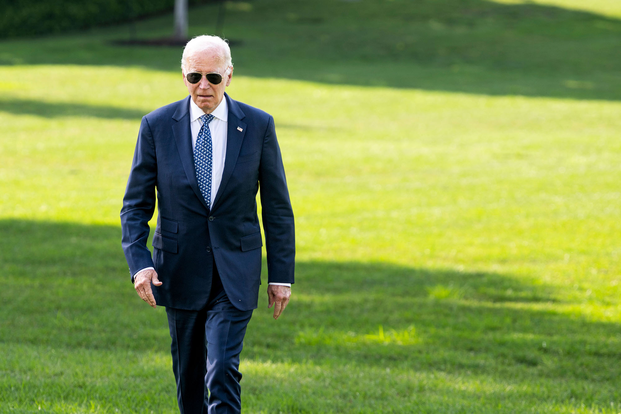 Photo: Former president Joe Biden walking across a green lawn