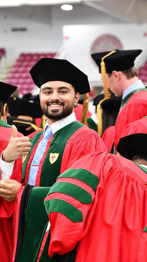 Vaibhav Gupta (CAMED’25) gives a thumbs up as he takes his seat at the MD/PhD convocation ceremony May 15 at BU’s Track & Tennis Center.