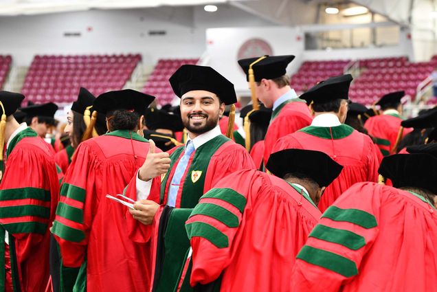 Vaibhav Gupta (CAMED’25) gives a thumbs up as he takes his seat at the MD/PhD convocation ceremony May 15 at BU’s Track & Tennis Center.