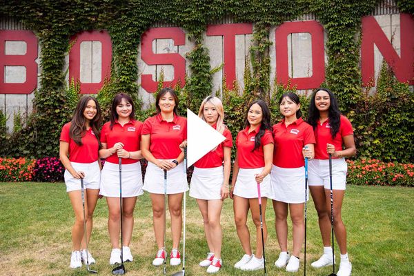 Photo: A group shot of the BU women's golf team in there uniforms with a wall in the background that reads BOSTON.