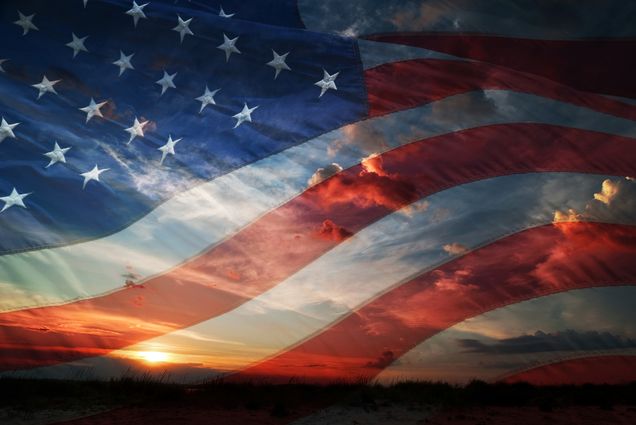 Photo: An American flag overlayed across an open sky with a sunset in the background