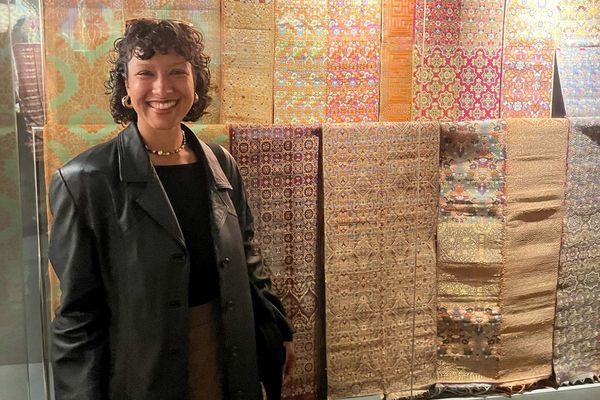Photo: A girl in a leather jacket smiling in front of textiles