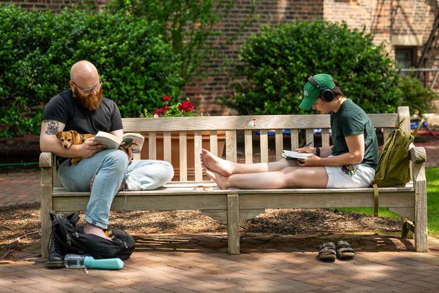 Photo: Two people sititng on a bench at BU Beach