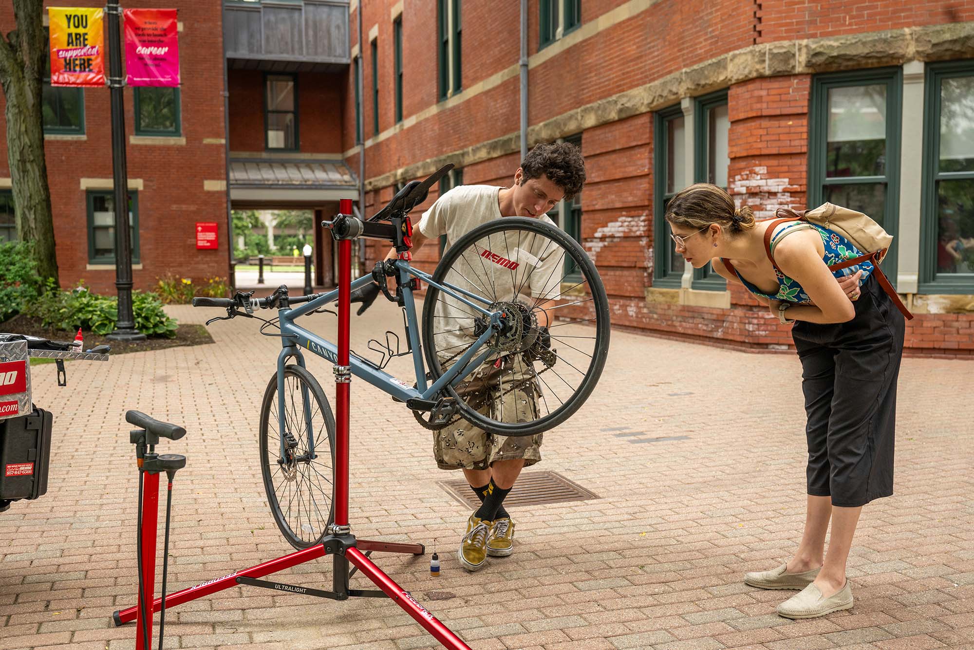 Photo: 6/26/25 -- Boston , Massachusetts Cameron Dumaine, expert mechanic with on demand bike repair business Nemo, works on Dr Maria Mesalles’ bike during a MED campus bike clinic June 26. Inspections, adjustments, alignments and oiling of bike components were open to faculty, staff, and students on Medical campus and employees at BMC. Mesalles is an internist at BMC. Photo by Cydney Scott for Boston University Photography