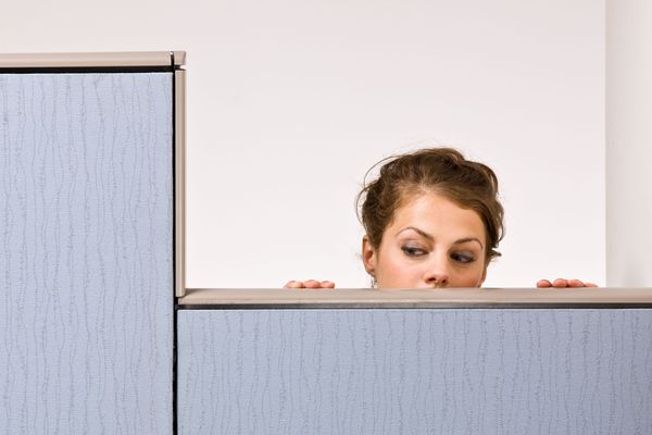 Photo: A businesswoman peering over cubicle wall