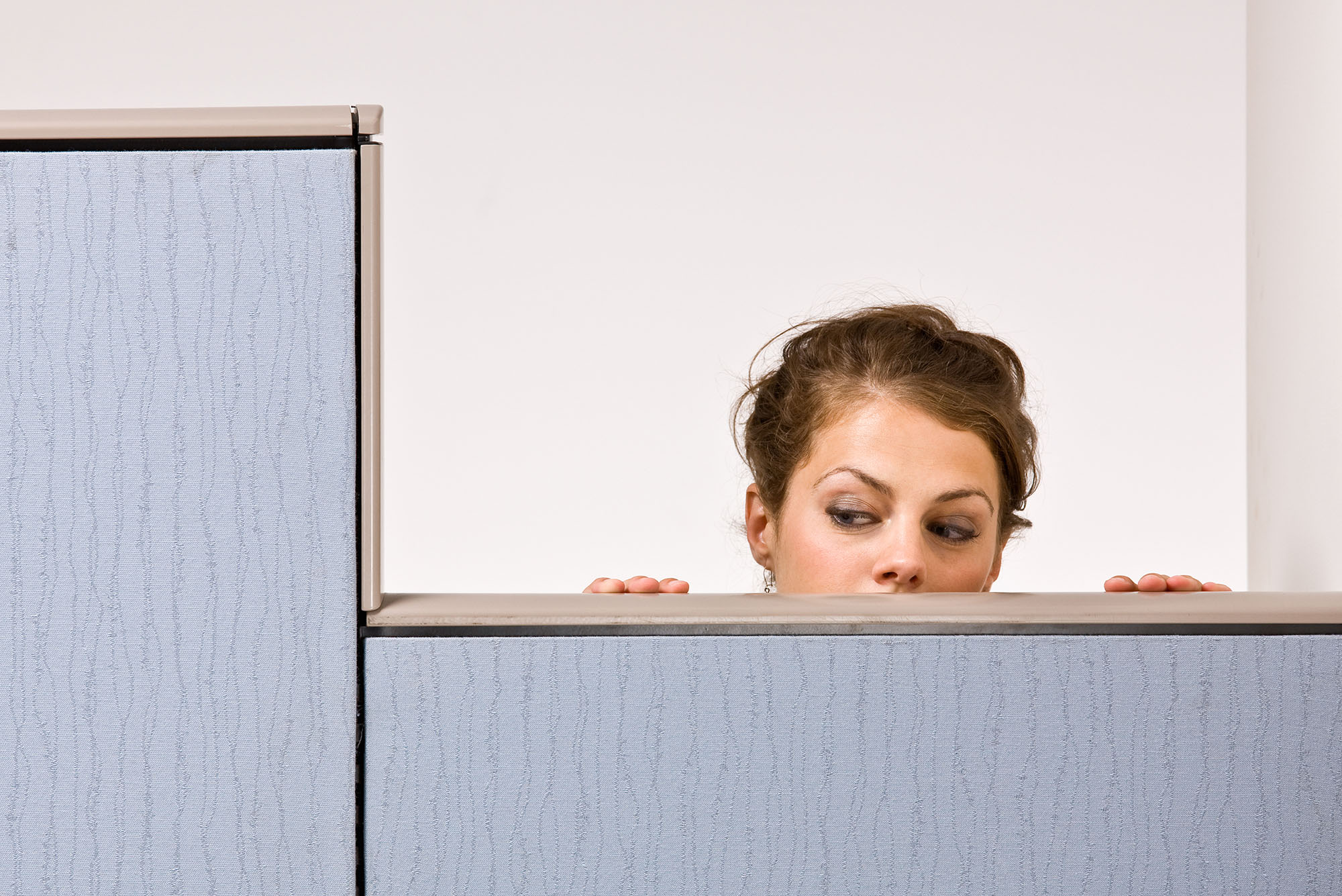 Photo: A businesswoman peering over cubicle wall