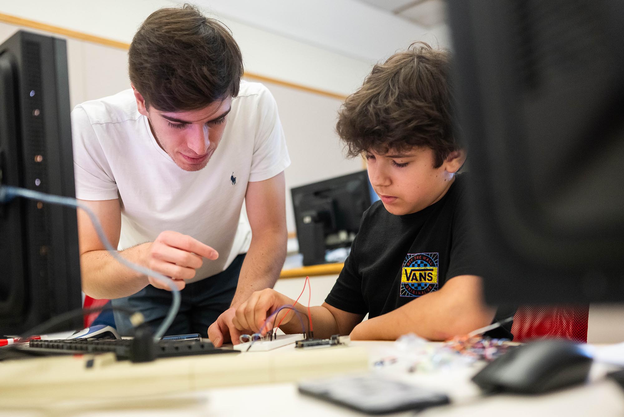 Photo: A young college students helps a younger middle school student on an engineering project.