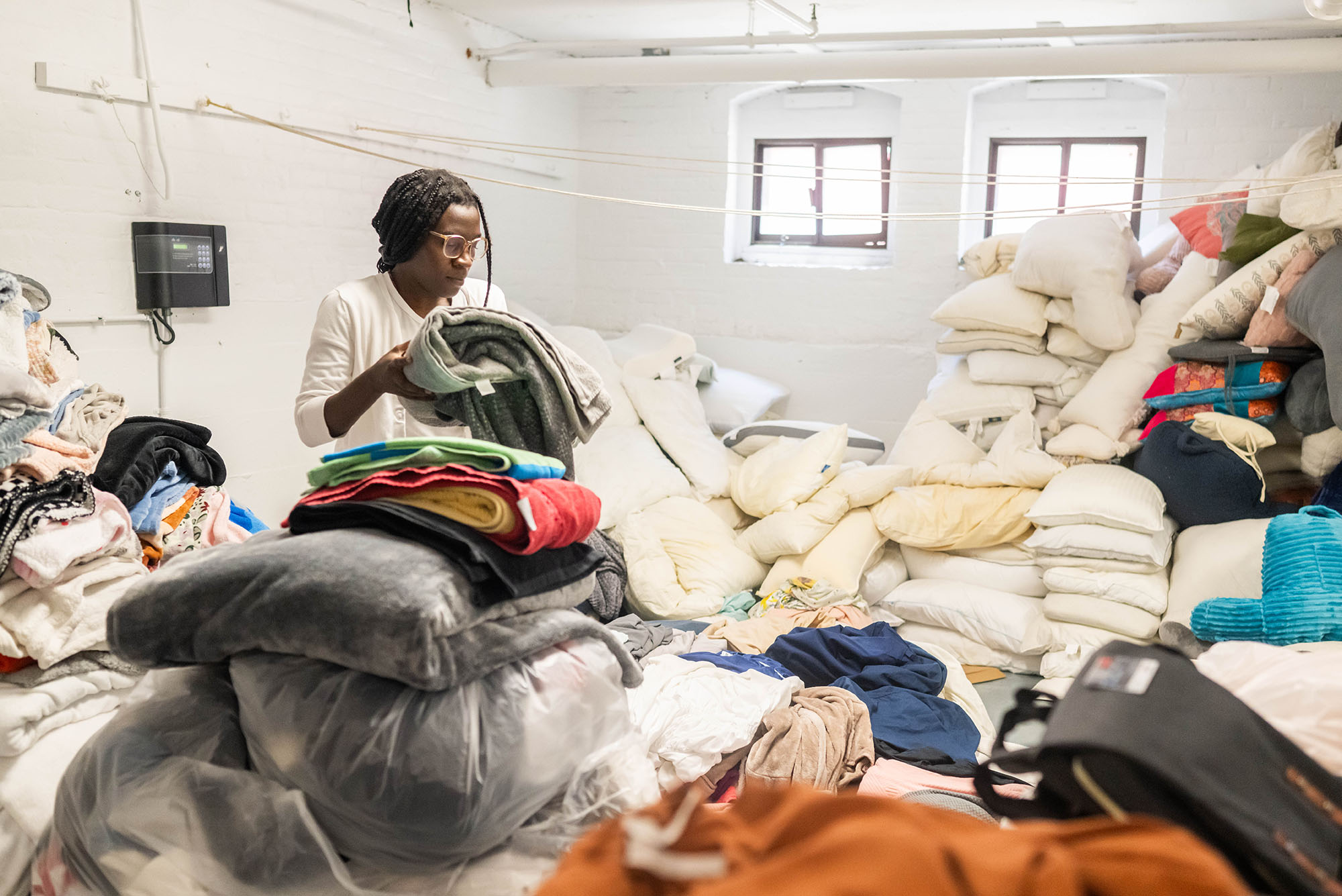 Photo: A woman sorts through assorted bags of textiles in a warehouse