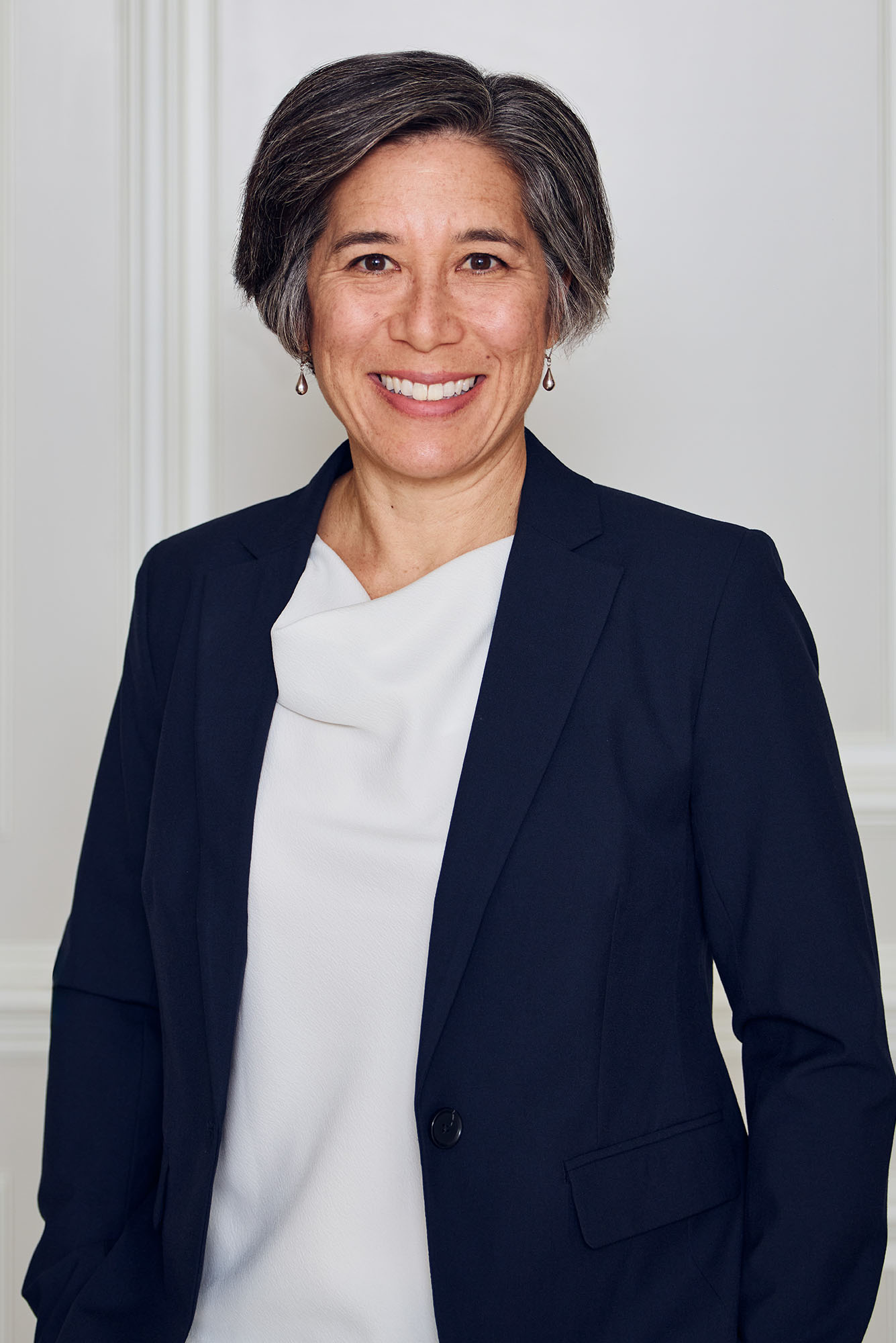 Photo: A portrait of a woman with short hair wearing a blazer and white blouse smiles for the photo.