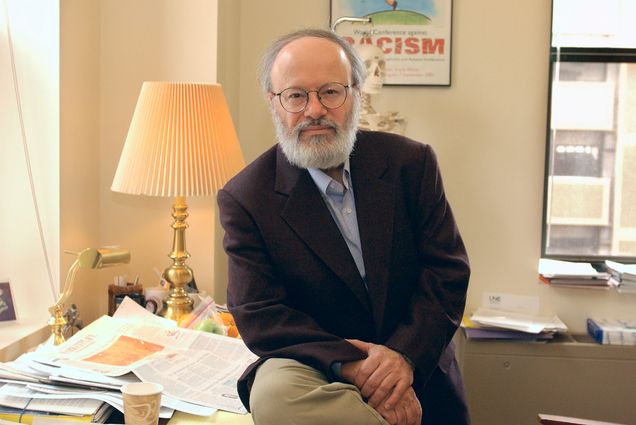 Photo: A man in a suit leaning against a desk