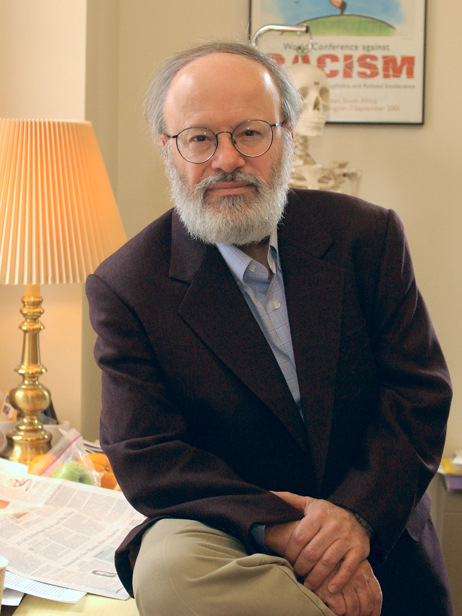 Photo: A man in a suit leaning against a desk