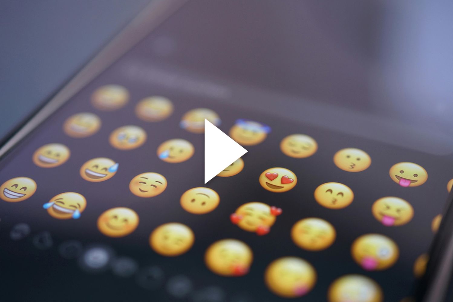 Photo: A phone open with emojis on it. There is a video play button over the image