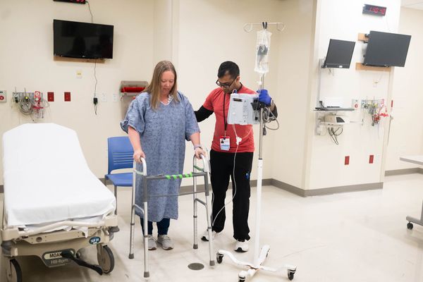 Photo: Krishn More (SAR 26) pretends to assist Corinne Fairweather, Manager of the Mobility Program during training at the Sims lab