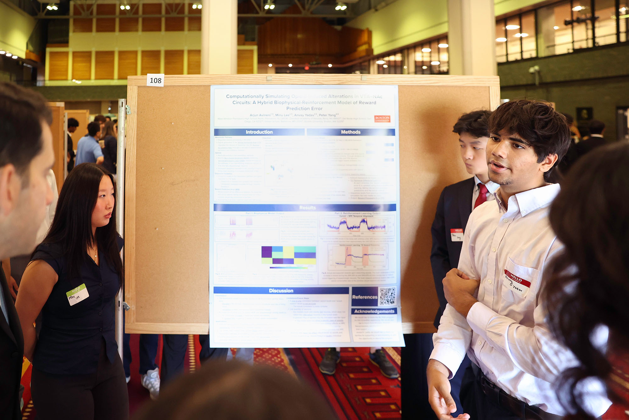 Photo: A group of students standing next to a poster board with a presentation on it