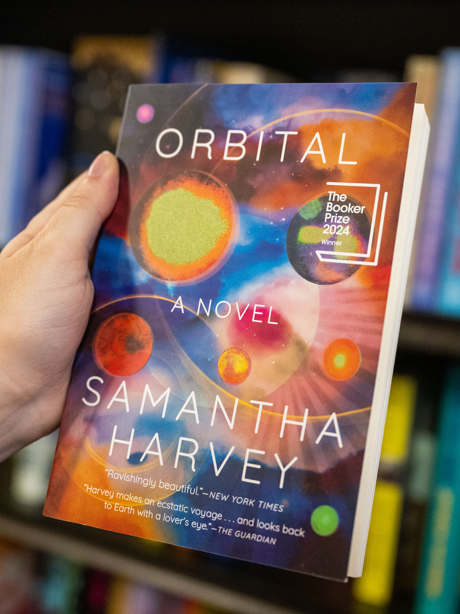 Photo: A hand holding the book "Orbital" by Samantha Harvey