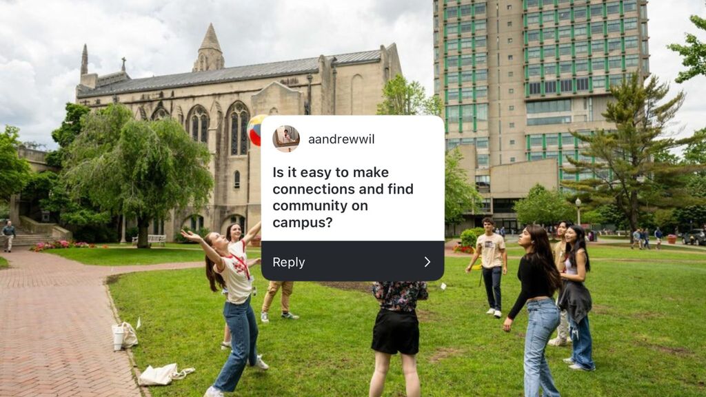 Students are enjoying a sunny day on a grassy campus quad, actively participating in a circle game with a colorful beach ball. The group is dressed casually for warm weather, and some bags and drinks sit on the brick pathway nearby. The quad is framed by a tall academic building featuring green accents, a gothic-style chapel, and leafy trees. The overlay features the question: “Is it easy to make connections and find community on campus?” from “aandrewwil.”