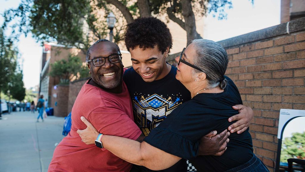 Photo: 3 people hug each other outside of a BU dormitory
