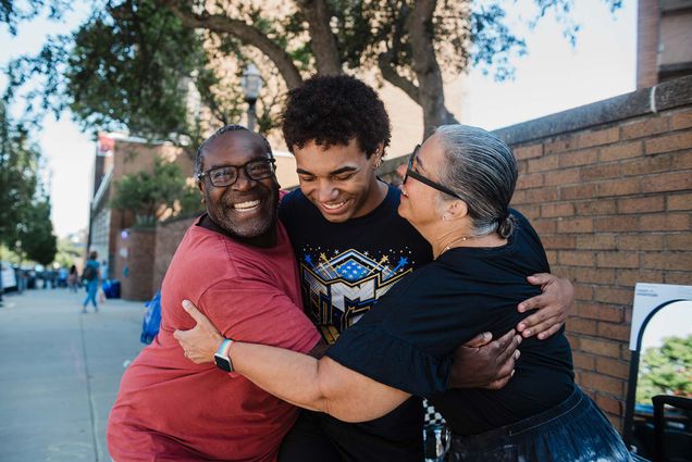 Photo: 3 people hug each other outside of a BU dormitory