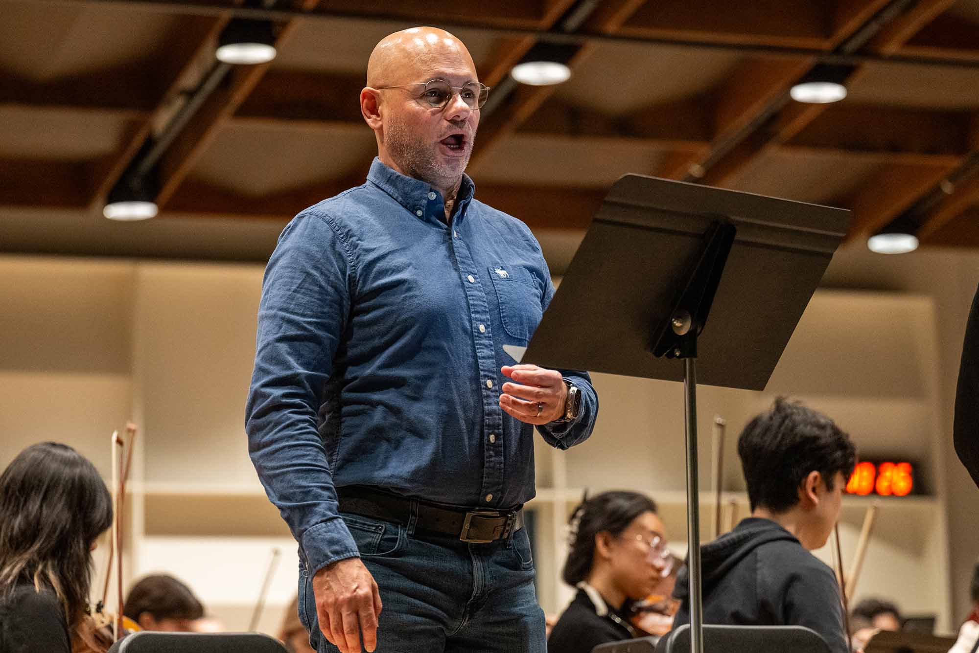 Photo: A man in a blue button up in the middle of performing an operatic.