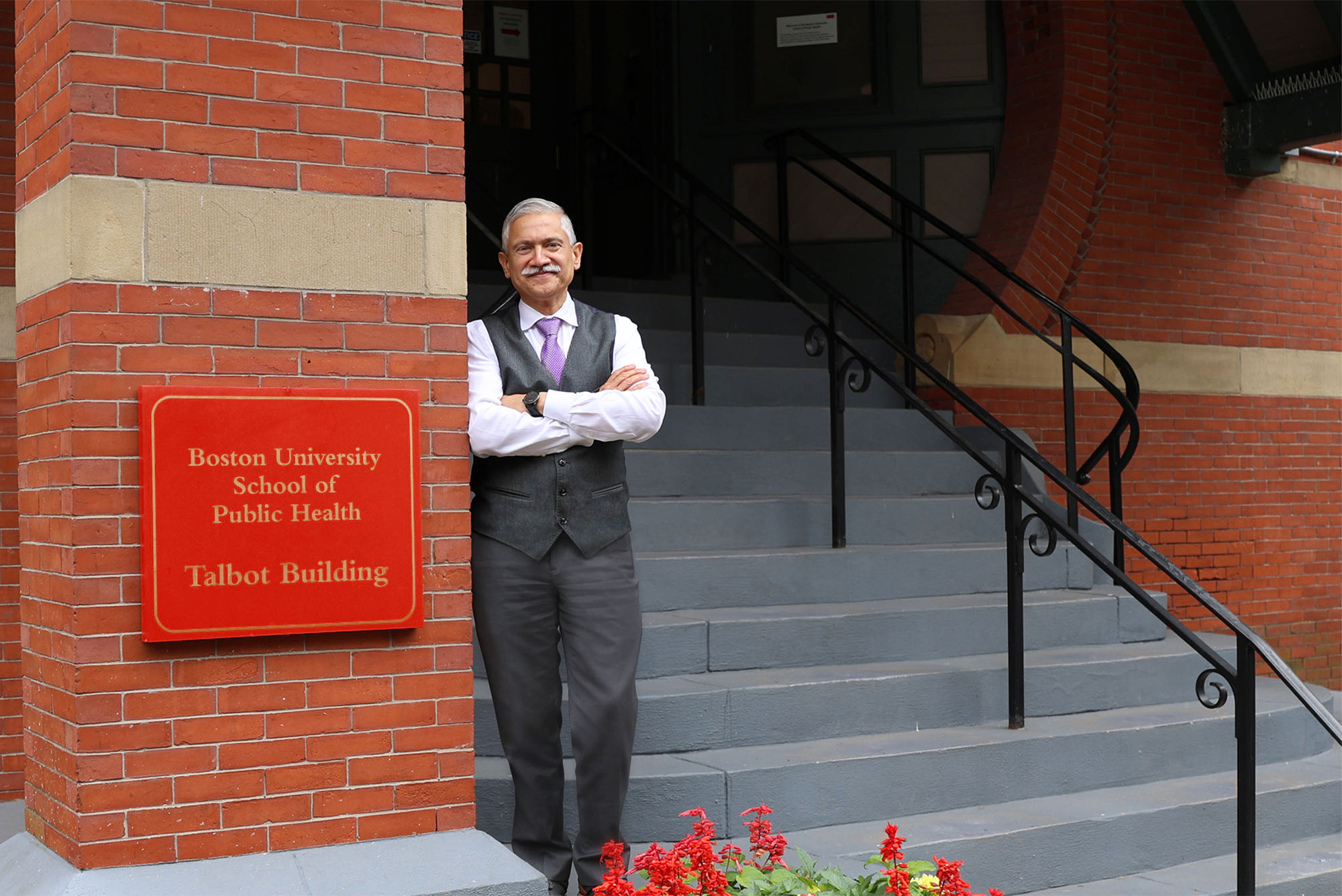 Photo: Dean Adnan Hyder posing next to Boston University's School of Public Health