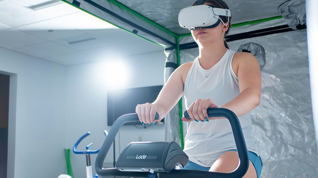 Photo: A woman on a cardio machine wearing a VR headset.