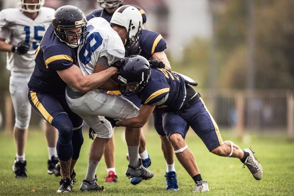 Photo: Football players tackling each other on a field