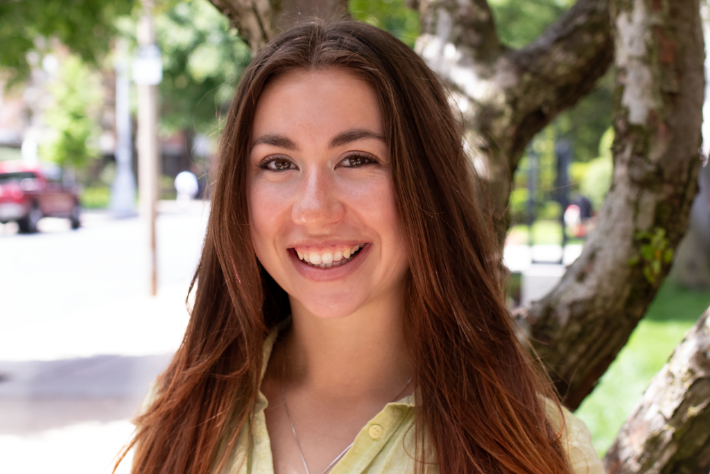 Photo: A portrait of a young woman with long brown hair smiling for the camera.