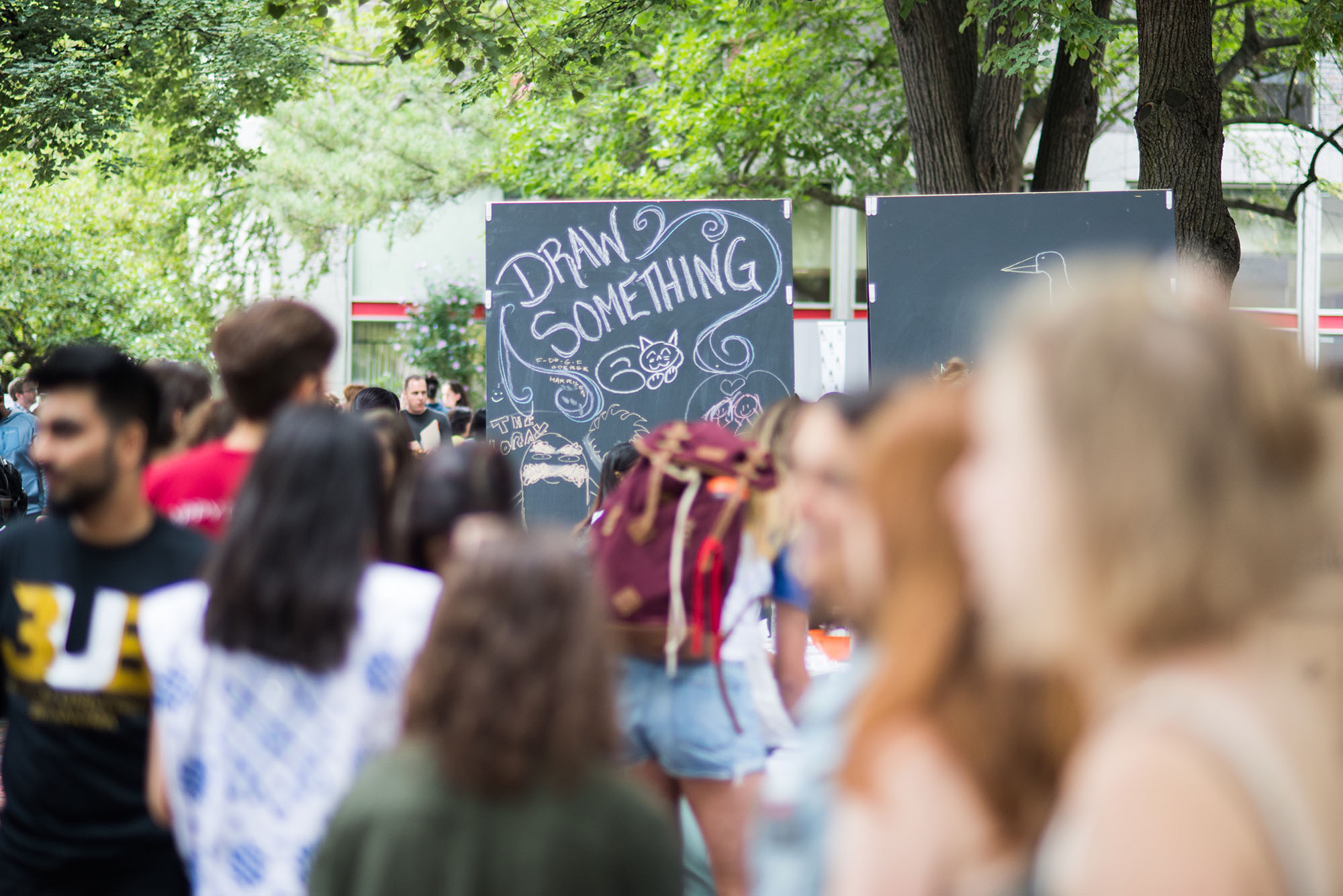 Photo: Large crowd of people in front of a sign that says "Draw Something"