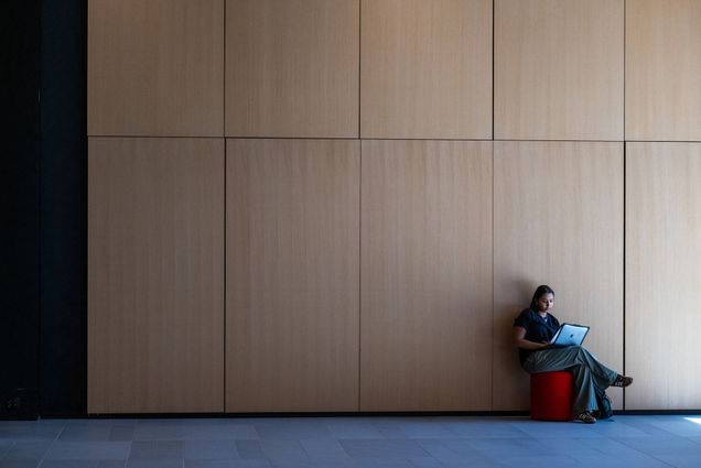 Photo: A college student studying in front of a large wooden wall