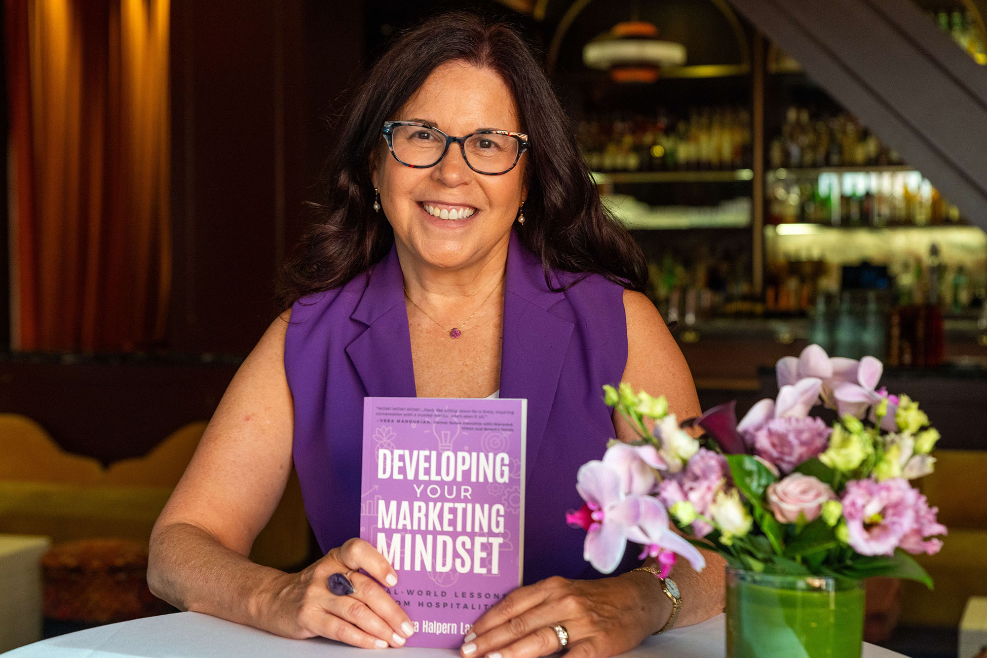 Photo: Leora Lanz, executive director of online programs at the School of Hospitality Administration and an associate professor of the practice of marketing, poses with her new book, Developing Your Marketing Mindset